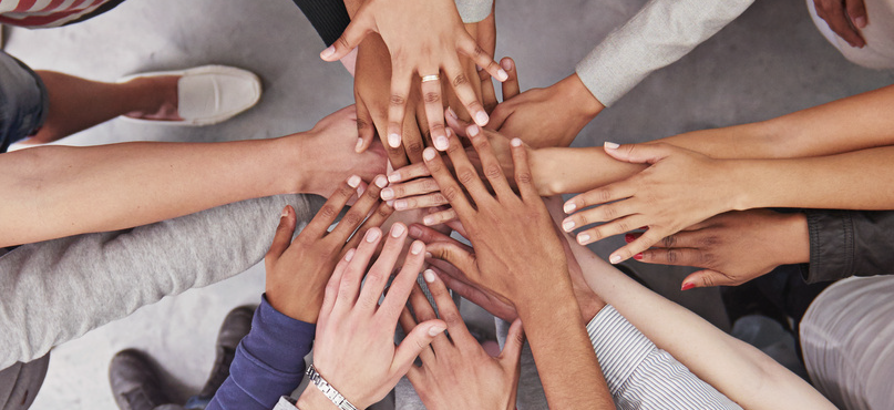 multiple people with their hands stacked on top of each other in the center