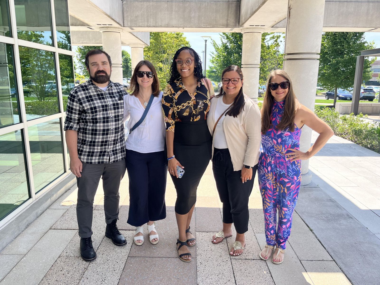 A group of people standing outside on a patio on a sunny day.