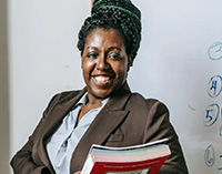 Mentor holding books in front of a whiteboard