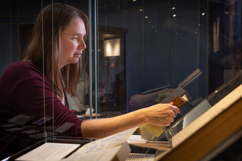 Photo credit: Robert DeSanto. Melissa Grafe places a book in a display case.