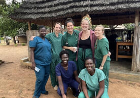 YSN students and three of their Ugandan preceptors--Monica, Joy, and Immaculate—pose in scrubs in a smiling group photo.
